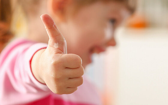 Kleines Mädchen zeigt mit ihrem Arm das Zeichen für Zustimmung oder OK